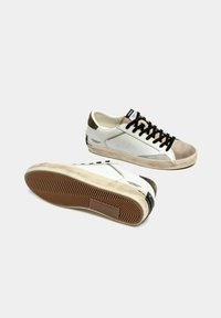 Sneaker in pelle bianca con accenti in suede beige, lacci neri, suole in gommaTexturizzata e un design minimalista caratterizzato da dettagli di cucitura laterale.