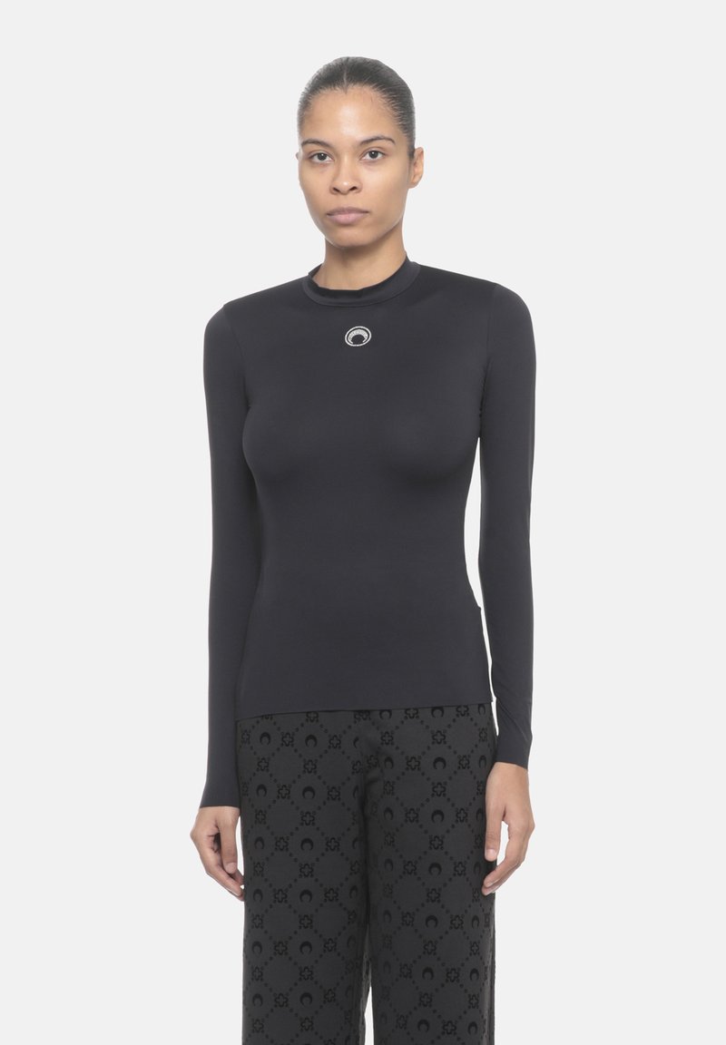 Top nero a maniche lunghe con collo alto, design aderente e un accento rotondo in argento al colletto. Tessuto morbido con stile minimalista.