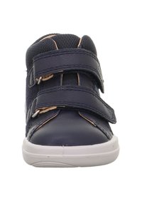 Marineblauwe schoen met twee klittenbandsluitingen, bovenwerk van textuurstof, gladde leren accenten en een witte rubberen zool. Klassiek sneakerdesign.