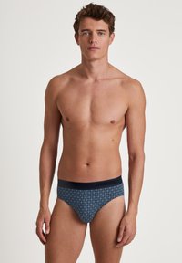 Slip da uomo blu navy con motivo geometrico, vita elastica e design aderente, realizzati in tessuto morbido e traspirante.