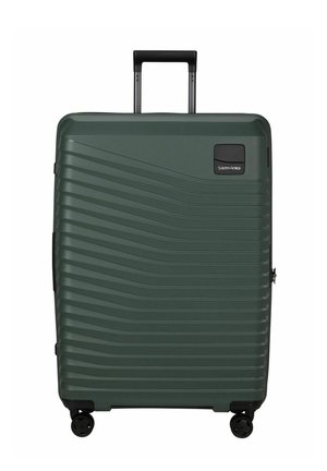 Valise rigide vert foncé avec des rainures horizontales, quatre roues noires pivotantes et une poignée télescopique noire déployée.