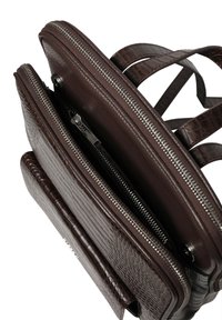 Barna bőr hátizsák krokodilbőr mintázattal, két cipzáros rekesszel és masszív pántokkal. A fém elemek fém cipzárakat tartalmaznak.