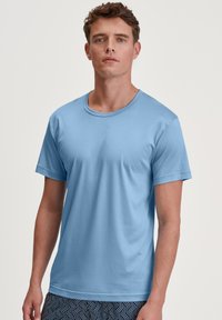 Lichtblauw T-shirt met korte mouwen, ronde hals, gemaakt van een gladde stof, met een ontspannen pasvorm. Draag het over een paar gestreepte shorts met een geometrisch ontwerp.