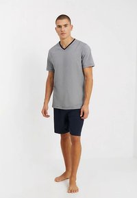 Szary T-shirt z krótkim rękawem i dekoltem w serek z czarną lamówką, zestawiony z granatowymi szortami. Oba wykonane z miękkiego, lekkiego materiału.