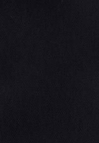 Gros plan sur un tissu noir montrant une texture tissée diagonale et des détails de couture fine.