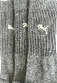 Drei Paare graue gerippte Socken mit weißen Puma-Logos, vertikal ausgerichtet.