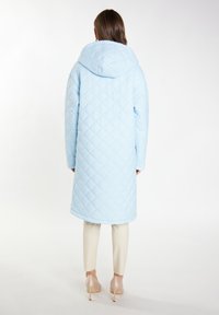 Cappotto lungo trapuntato blu chiaro con cappuccio, caratterizzato da motivi a rombi, texture liscia e silhouette affusolata.