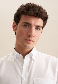 Witte button-up shirt met een gestructureerde afwerking, kleine kraag en een borstzak. Heeft heldere knopen en een rechte snit.