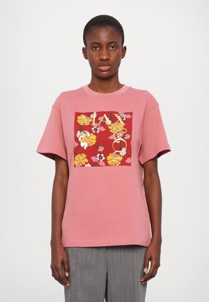 Pink cotton t-shirt featuring a square floral graphic in red, yellow, and white with "MAX" in bold letters. Short sleeves and relaxed fit.