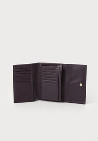 Portefeuille en cuir violet avec surface texturée, comportant plusieurs emplacements pour cartes, une poche centrale et un fermoir à bouton pression doré.
