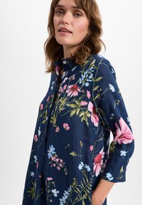 Hemdblusenkleid mit kurzen Ärmeln in Blau mit bunten Blumenmustern, einem Kragen und einer Knopfleiste auf der Vorderseite.