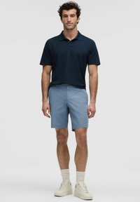 Tume sinine polo-särk, helesinised lühikesed püksid, valged tossud ribakudumisega. Püksid on siledapealsete tekstuuriga, samas kui särk näeb välja pehme.