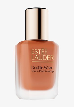 Estee Lauder Double Wear foundation i en kantet glasflaske med en brun-orange væske. Guld låg og logo med sort tekst på siden.