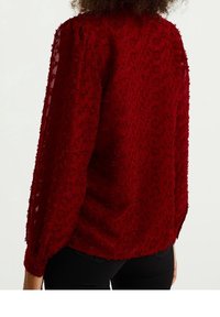 Rote Textilbluse mit Struktur, aus transparentem Stoff, mit floralem Muster, Ballonärmeln und Knopfmanschetten, entworfen für eine lockere Passform.