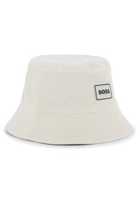 Chapeau seau en velours côtelé blanc avec une large bordure, présentant un patch logo BOSS rectangulaire noir et blanc sur le côté. Surface texturée.