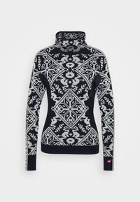 Svarte og hvite mønstrede genser med høy hals som har geometriske og blomsterdesign, ribbestrikkede mansjetter og en liten rosa detalj på ermet.