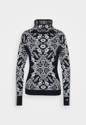 Svarte og hvite mønstrede genser med høy hals som har geometriske og blomsterdesign, ribbestrikkede mansjetter og en liten rosa detalj på ermet.