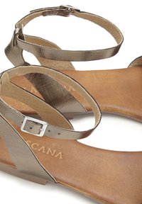 Strappy sandals with metallic bronze leather upper, a smooth tan insole, and a small silver buckle on the ankle strap.