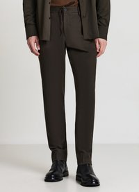 Braune, maßgeschneiderte Hose mit Kordelzugbund, glatter Textur und geraden Beinen, kombiniert mit schwarzen Lederschuhen.