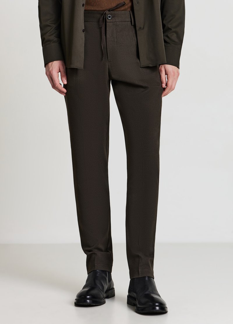 Braune, maßgeschneiderte Hose mit Kordelzugbund, glatter Textur und geraden Beinen, kombiniert mit schwarzen Lederschuhen.