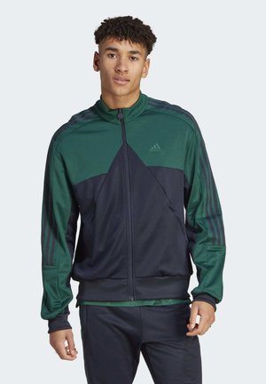 Giacca da track Adidas con una parte superiore verde e una parte inferiore blu navy, dotata di tre righe verticali su ciascun maniche e tessuto morbido.
