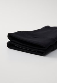 Zwarte stretchleggingen netjes opgevouwen. De stof lijkt glad met een lichte glans, met een eenvoudig ontwerp en geen zichtbare patronen.