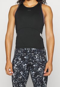 Svart atletisk linne med racerback-design och grå accenter, ihop med figurnära leggings med ett abstrakt mönster i svart och grått.