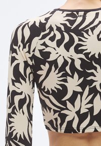 Μαύρο και μπεζ crop top με υφασμάτινη υφή και έντονο φυλλώδες μοτίβο, στρογγυλή λαιμόκοψη και μακριά μανίκια.