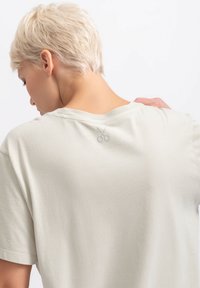 Lichtgrijs T-shirt gemaakt van zachte katoen, met een ontspannen pasvorm en een kleine schaarafbeelding op de bovenrug. Korte mouwen.