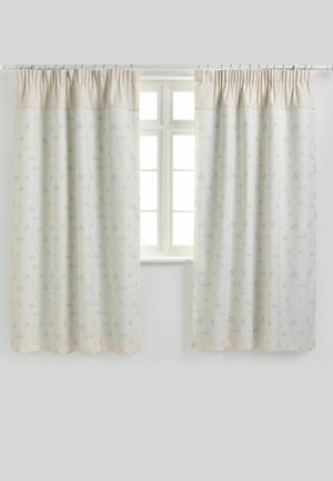 Twee beige en witte gordijnen met subtiele dierenpatronen bedekken gedeeltelijk een wit raam met vier ruiten tegen een lichtgrijze muur.