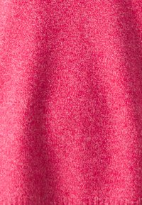 Miękki różowy dzianinowy materiał o jednolitej fakturze. Kolor jest jasny, z subtelnymi odcieniami na całej powierzchni.