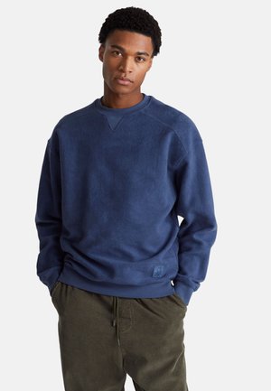 Marineblauwe fleece sweatshirt met een geribbelde ronde hals en manchet mouwen. Bevat een klein logo-label aan de onderlinkerkant. Zachte textuur.