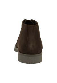 Brown suede ankle boots with a smooth texture, rounded heel, and a durable rubber sole. Rear view shows stitching detail and minimalist design.