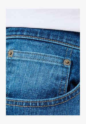 Niebieskie jeansy z denimu z małą tylną kieszenią, ozdobione złotym przeszyciem i metalowymi nitemi. Gładka faktura i klasyczny krój.