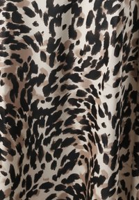 Satin stoff med en beige bakgrunn som har et svart og brunt leopardmønster; glatt tekstur med varierende flekkstørrelser.
