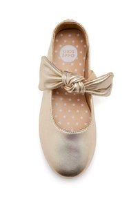 Ballet flat dorato con un accento di fiocco annodato, tomaia metallica liscia, punta arrotondata e una soletta decorata con stelle bianche su uno sfondo chiaro.