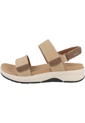 Sandale beige avec des brides réglables sur les orteils et la cheville, semelle intérieure rembourrée et semelle en caoutchouc noire et blanche.