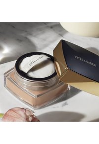 Pojemnik na puder Estee Lauder z przezroczystą podstawą i złotymi akcentami. Wieczko jest granatowe ze złotym napisem. Wewnątrz znajduje się okrąła, miękka gąbka do aplikacji.