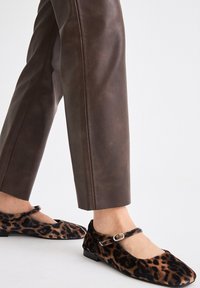 Bailarinas de estampado de leopardo fabricadas en tela suave, con suela plana y una correa a juego adornada con un detalle de hebilla decorativa.