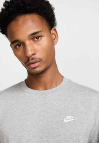Grå crew neck t-shirt i bomuld med kortærmer. Har et lille hvidt Nike-logo på venstre bryst. Glat tekstur.