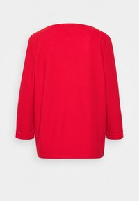 Top rosso in tessuto testurizzato con scollatura ampia e maniche a tre quarti. Taglio dritto, dettagli minimi, rifinito con risvolti.