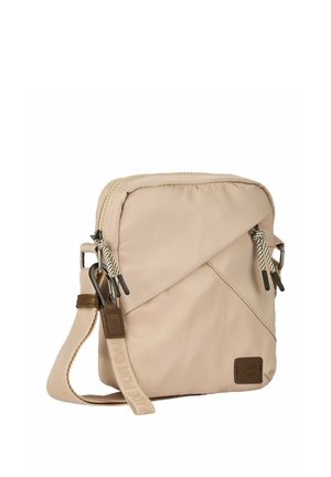 Beżowa kompaktowa torba na ramię z ukośną przednią kieszenią, podwójnymi suwakami z sznurkami, regulowanym paskiem oraz brązową naszywką z logo z przodu.