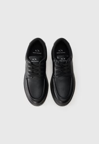 Par crnih kožnih Armani Exchange čizama sa vezicama na bijeloj pozadini, snimljenih s gornje strane.