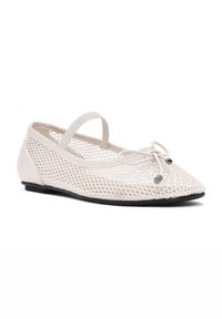 Bailarina plana blanca de malla con punta redonda, tira elástica y moño decorativo, que presenta una suela negra lisa y un diseño ligero.