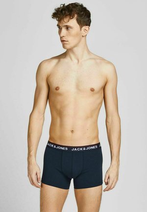 Mörkblå bomullsboxershorts med elastisk midja som har "JACK & JONES"-logotypen i vitt. Modellen står utan tröja mot en neutral bakgrund.