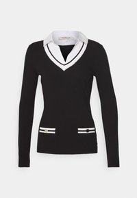 Pull noir à manches longues avec un col en V et un col blanc, présentant des rayures blanches et des accents de boutons dorés sur les poches. Texture lisse.