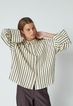 Striped long-sleeve shirt in light yellow with dark brown vertical stripes. Features a classic collar and loose fit. Soft texture, button closure.
