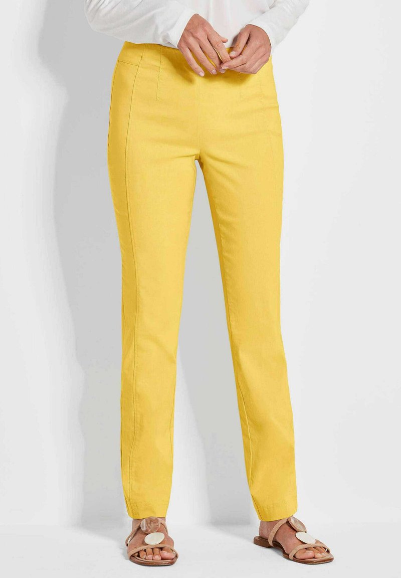 Geel slim fit broek met voorzakken en een soepele textuur. Gecombineerd met beige sandalen met een grote ronde accenten.