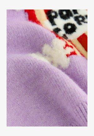 Lila pletenina z mehko teksturo in vidnimi vlakni, ki ima barvit pleten vzorec z akcenti rdeče in smetane.