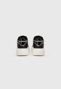 Black leather sneakers with a smooth texture and white platform sole. Featuring contrasting stitching and embossed branding on the heel.